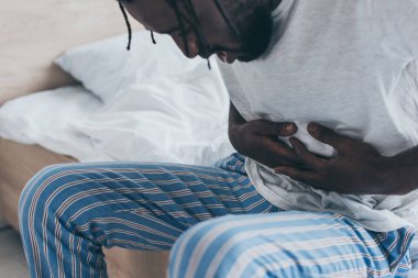 yatak odasında mide ağrısı muzdarip Afrikalı Amerikalı adam kısmi görünümü
