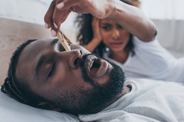 selective focus of snoring african american man near wife holding wooden pin clipart