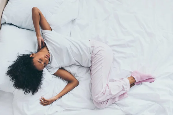 침구에 누워있는 통증을 아프리카 미국인 여성의 — 스톡 사진