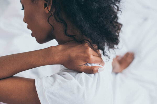 selective focus of african american woman suffering from neck pain in bedroom
