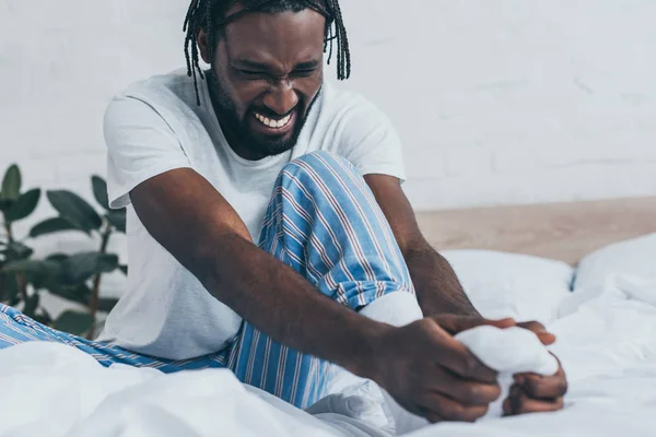 Young African American Man Suffering Foot Pain While Sitting Bedding — Stock Photo, Image