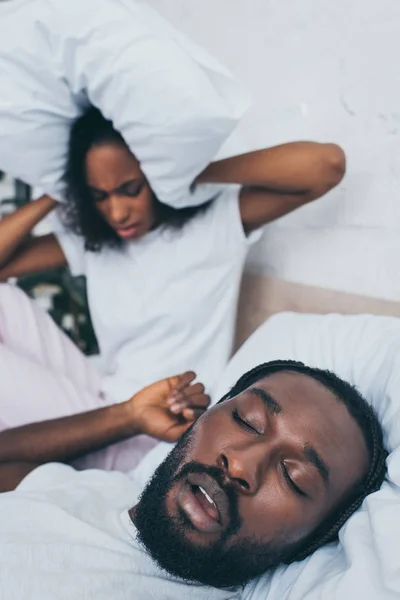 Horlama Kocası Yakınında Yatakta Otururken Yastık Ile Baş Kapsayan Afrikalı — Stok fotoğraf