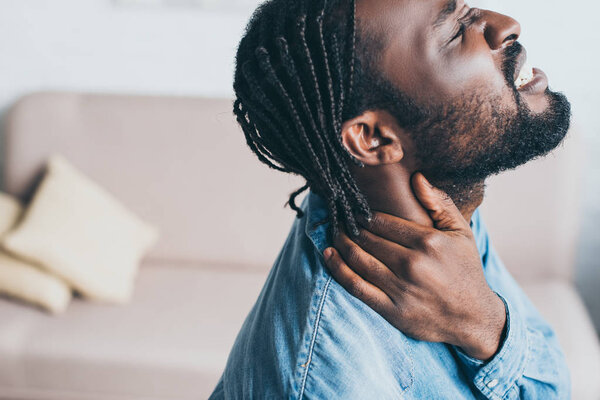 handsome african american man suffering from neck pain with closed eyes