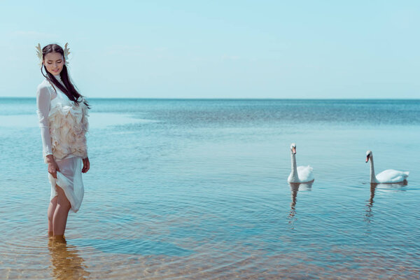 adult woman in white swan costume standing in river near birds