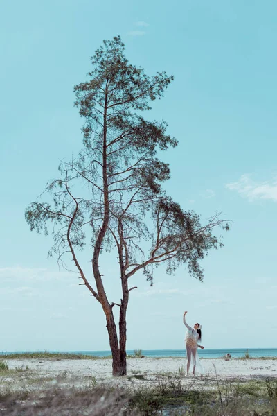 Kumlu Plajda Ağaç Yakınında Duran Beyaz Kuğu Kostümlü Esmer Kadın — Stok fotoğraf