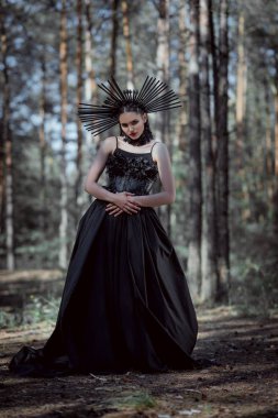 cadı kostümlü zarif kadın orman arka planda duran, kameraya bakarak