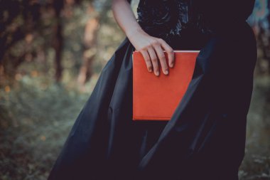 kırmızı kitap ile ayakta cadı kostümü yetişkin kadın kırpılmış görünümü