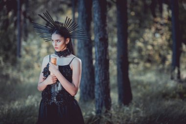 cadı kostümü güzel kadın orman arka planda duran, uzağa bakarak, kaydırma tutarak