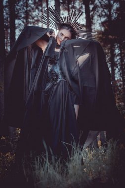 cadı kostümü ve taç üzerinde siyah tekstil yakın yüzü ile el ele tutarak, uzağa bakan esmer kadın