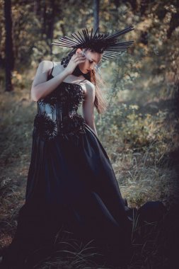siyah cadı kostümlü yetişkin kadın orman arka planda duran, uzağa bakıyor
