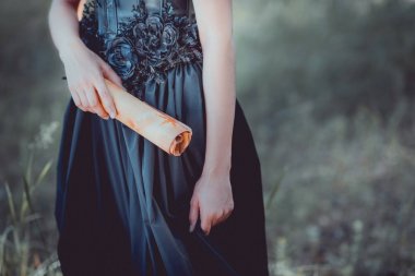 cropped view of woman in black witch costume standing with scroll in hand clipart