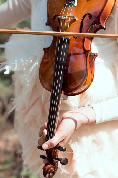 обрезанный вид элегантной женщины в белом лебедином костюме, играющей на скрипке
