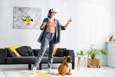 renkli saçlı kız ve Vr kulaklık oturma odasında köpek yanında duran