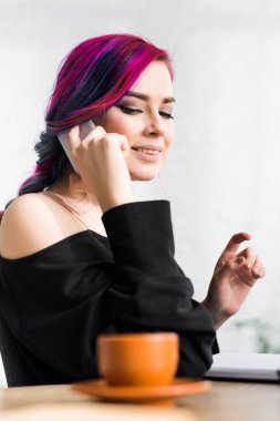 güzel kız masa başında oturan seçici odak, gülümseyerek ve uzağa bakarak