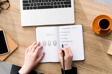 cropped view of girl writing packing list in notebook  clipart