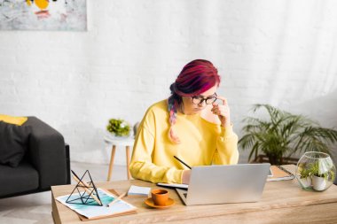 hipster kız oturma odasında masanın arkasında otururken pensively notlar yapma