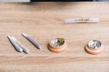 joints with medical marijuana and herb grinder on table  clipart