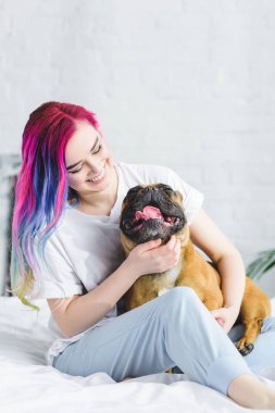 neşeli hipster kız yatakta oturan ve fransız bulldog petting 