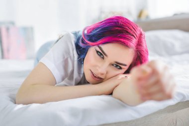 renkli saç yatakta döşeme ve kamera bakarak güzel kız seçici odak 