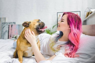 yatakta yatan ve Fransız bulldog bakarak çekici kız yan görünümü 