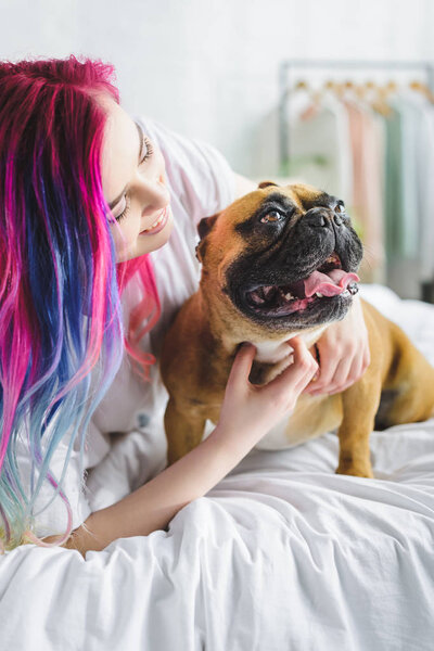 girl with colorful hair petting and looking at cute french bulldog