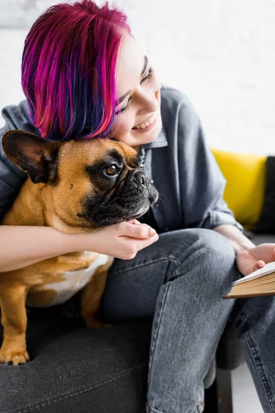 Meisje Met Kleurrijke Haren Knuffelen Bulldog Glimlachend Holding Boek — Stockfoto