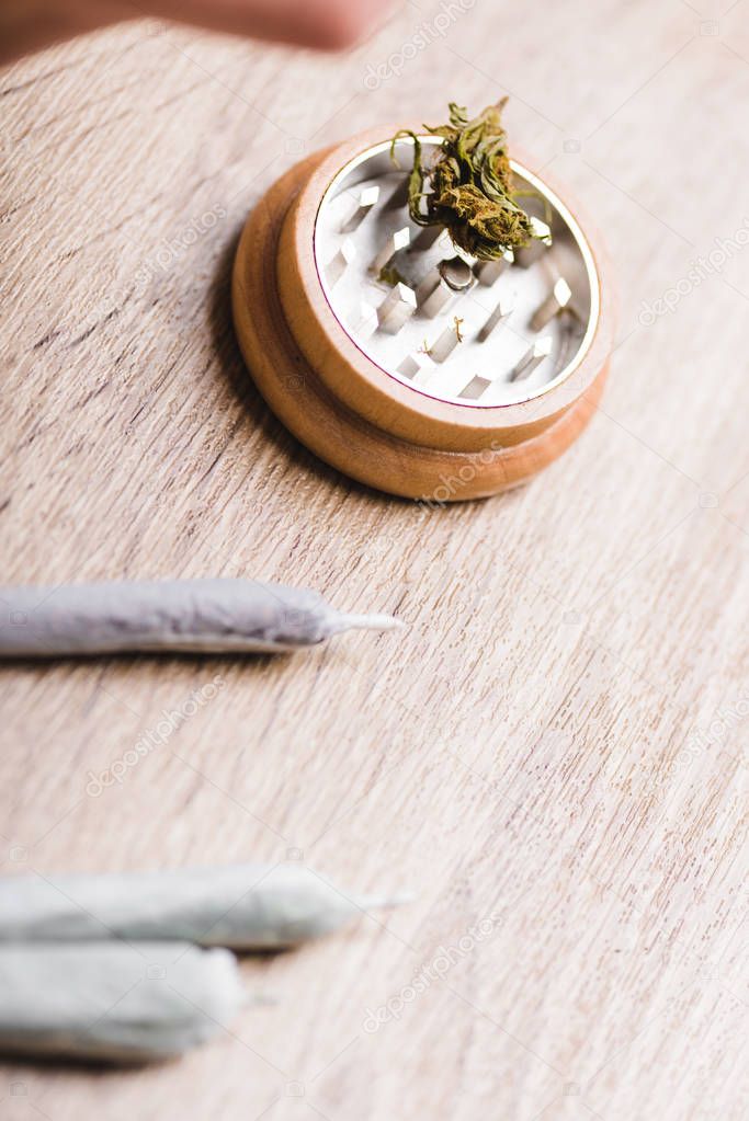 close up view of herb grinder and joints with medical marijuana