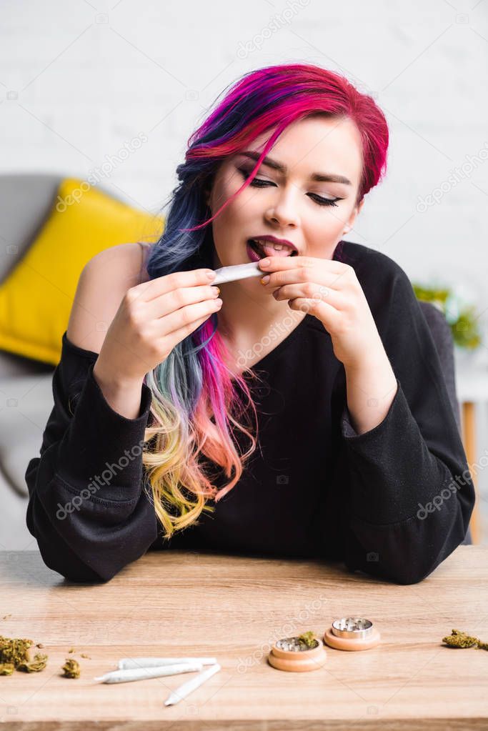 beautiful girl with colorful hair licking joint with medical marijuana 