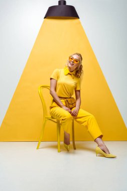 beyaz ve sarı sandalyede oturan güneş gözlüğü pozitif sarışın kadın 