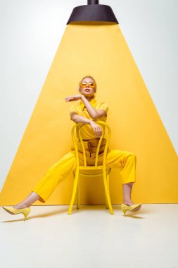 beyaz ve sarı sandalyede oturan güneş gözlüğü çekici sarışın kadın 