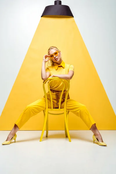 Mulher Loira Tocando Óculos Sol Sentado Cadeira Branco Amarelo — Fotografia de Stock