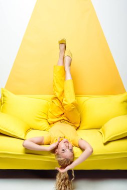 beyaz ve sarı kanepeüzerinde baş aşağı yatan çekici sarışın kadın 