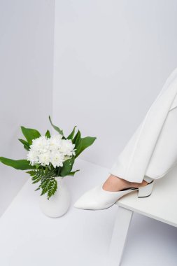 beyaz çiçeklerle vazo yakınında kadın kırpılmış görünümü 