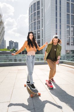 woman and man riding on skateboards on roof