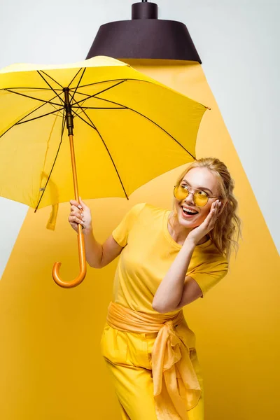 Cheerful Blonde Girl Looking Umbrella While Touching Sunglasses White Yellow — Stock Photo, Image