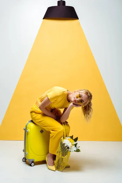 Blondes Mädchen Sitzt Auf Reisegepäck Und Hält Schnurtasche Mit Blumen — Stockfoto