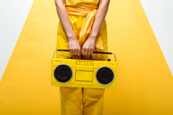 cropped view of woman posing with retro boombox on white and yellow 