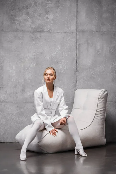 灰色の柔らかい豆袋の椅子に座っている魅力的な若い女性 — ストック写真
