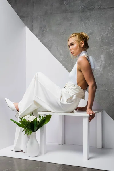 Femme Élégante Assise Près Vase Avec Des Fleurs Sur Blanc — Photo