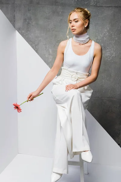 Blonde Hübsche Mädchen Sitzt Und Hält Rosa Blume Auf Weiß — Stockfoto