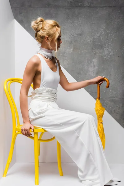 Hermosa Mujer Sentada Silla Sosteniendo Paraguas Amarillo Blanco Gris — Foto de Stock