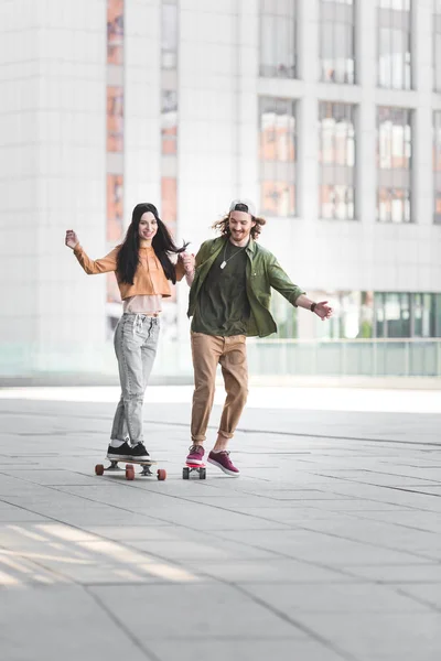 Šťastný Muž Držící Ruce Krásnou Ženou Jezdila Skateboard Městě — Stock fotografie