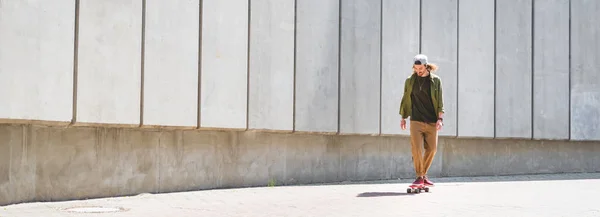 Панорамный Вид Красивого Мужчину Катающегося Скейтборде Возле Бетонной Стены — стоковое фото