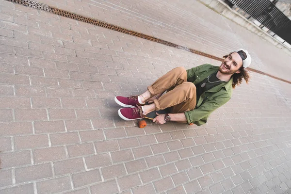 Visão Alto Ângulo Homem Alegre Sentado Montando Skate — Fotografia de Stock