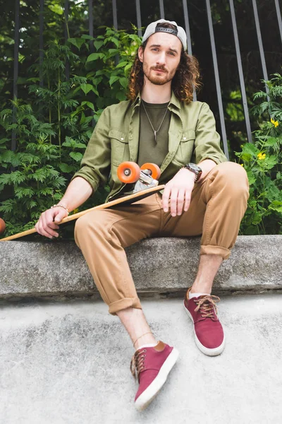 Lage Hoek Weergave Van Knappe Man Holding Skateboard Handen Kijkend — Stockfoto
