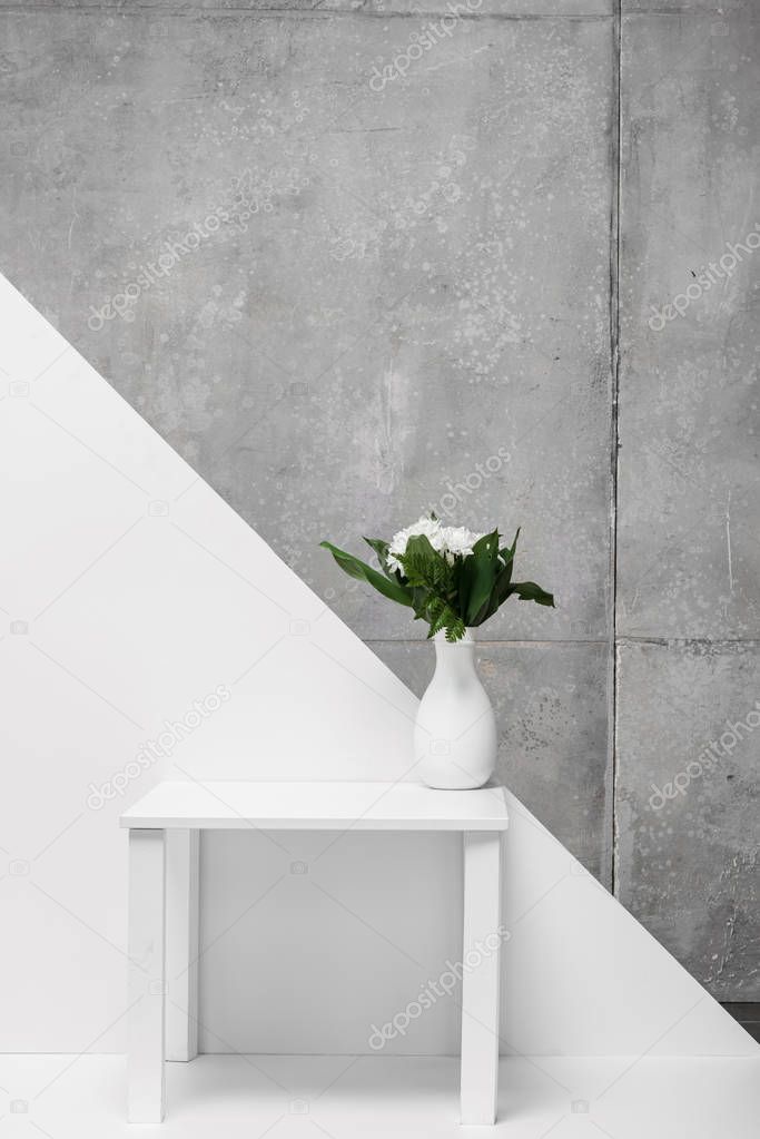 bouquet of flowers in vase on table on white and grey 