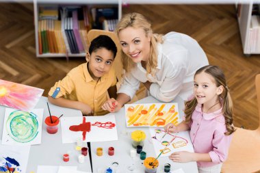 overhead view of cheerful teacher smiling with happy multicultural kids  clipart