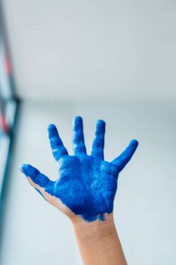 mavi guaj boya ile boyalı el gösteren çocuğun kırpılmış görünümü 