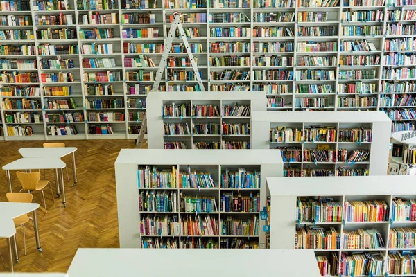 Kütüphanede Ahşap Masa Sandalyeler Yakınında Kitap Koleksiyonu Ile Raflar — Stok fotoğraf
