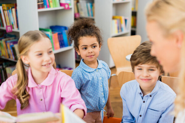 selective focus of happy multicultural kids smiling near woman 